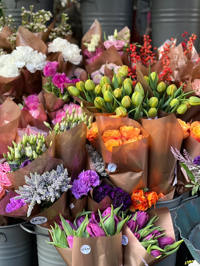 gallery-5 Vibrant flower bouquets in various colors arranged beautifully in buckets for sale at a florist.
