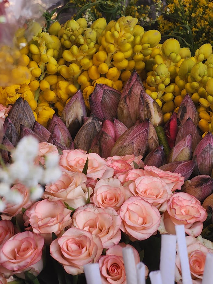 why-choose-us A colorful display of roses, lotus buds, and yellow flowers in a market setting.