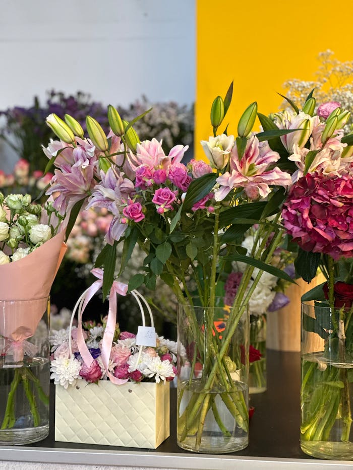 Vibrant display of pink lilies and roses in glass vases, perfect for floral enthusiasts.
